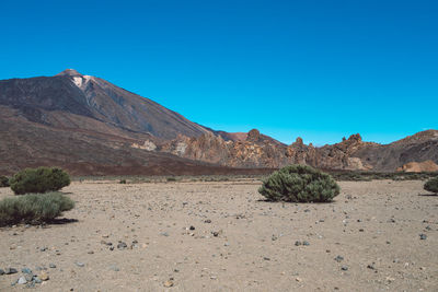 Scenic view of desert against clear blue sky