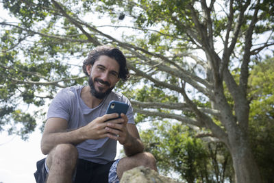 Young man at a park on a beautiful sunny day with mobile phone. home office. green and nature l