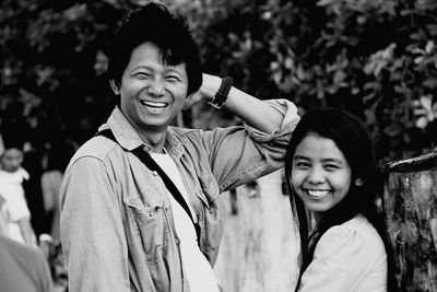 Portrait of smiling couple standing against trees