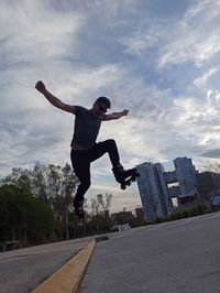 Full length of man jumping in city against sky