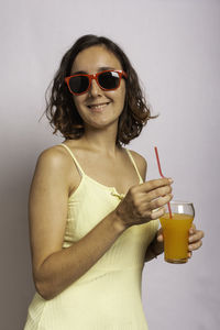 Mid adult woman wearing sunglasses standing against wall