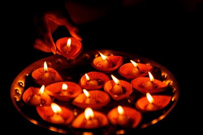 Cropped hand of woman arranging diyas in plate