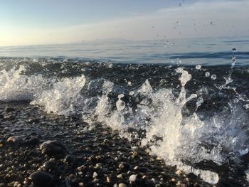 Close-up of waves splashing on shore against sky