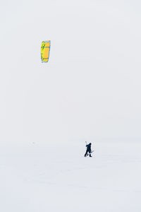 Person paragliding on snow against sky