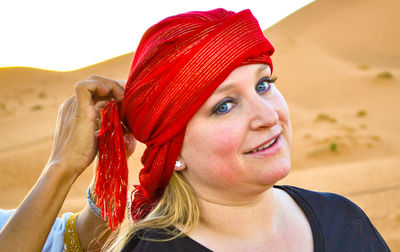 Midsection of man helping smiling woman wearing headscarf at desert