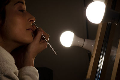 Close-up of woman putting make-up in front of mirror