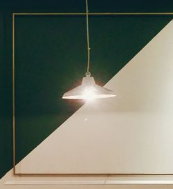 Low angle view of illuminated light bulb hanging from ceiling