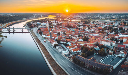 High angle view of townscape by river against sky during sunset