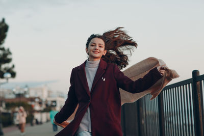 Portrait of smiling young woman standing against railing