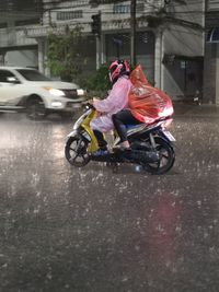 Man riding motorcycle on street in rain
