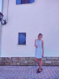 Full length of young woman standing against wall