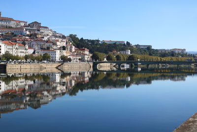 Buildings by river against blue sky