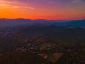 The aerial view of rural house and farm surrounding with mountain with red sky sunset background