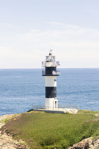 Lighthouse by sea against sky