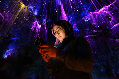 Portrait of young woman using smart phone at night