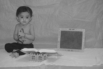 Portrait of cute boy sitting on bed at home