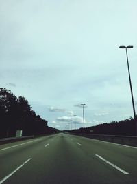 Road by trees against sky