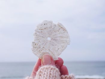 Close-up of woman holding shell against sea