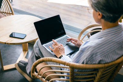 Midsection of woman using laptop while sitting on table