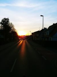 Street amidst buildings against sky during sunset