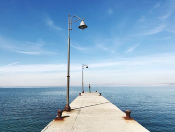 Side view of mid adult man standing on pier by sea against sky