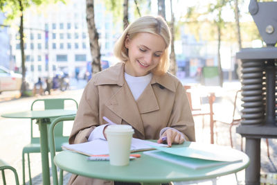 Young woman using mobile phone while sitting on table