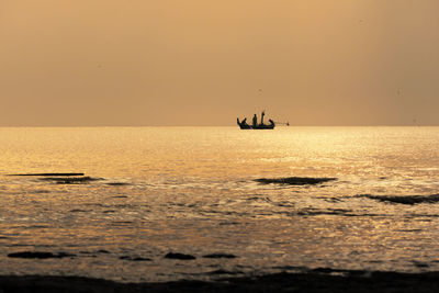 Silhouette boat in sea against sky during sunset