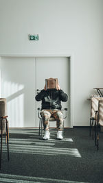 View of people sitting on chair against wall