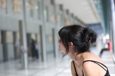 Side view of woman looking through window