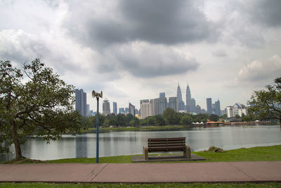 Buildings by river against sky in city