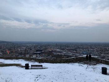 Snow covered buildings in city against sky