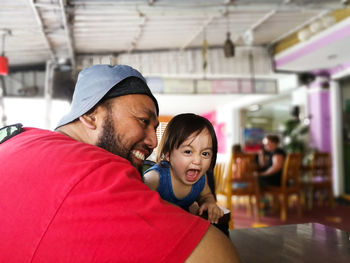 Portrait of cute daughter screaming by father at restaurant