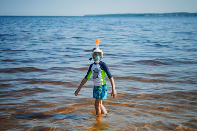 Cute little caucasian boy wearing snorkling mask going out from the sea