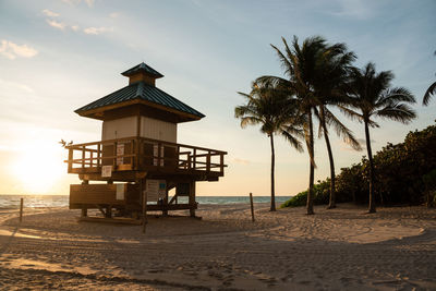 Lifeguard hut on beach against sky during sunset