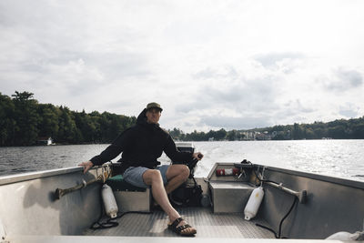 Man riding motorboat on lake rosseau against cloudy sky