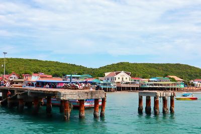 Stilt houses by sea against sky