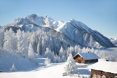 Winter mountain landscape with traditional alpine hut and snowy forest