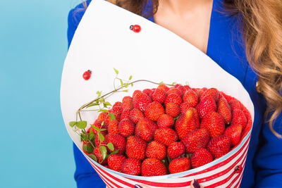 Midsection of woman holding strawberries in bowl