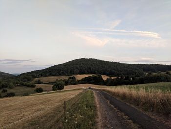 Road amidst field against sky