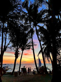 Silhouette people on beach against sky during sunset