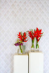 Close-up of red flower vase on table against wall