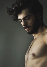 Close-up of shirtless man against gray background