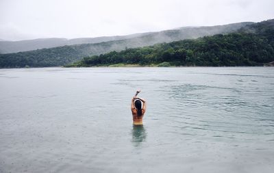 Rear view of woman in lake against sky