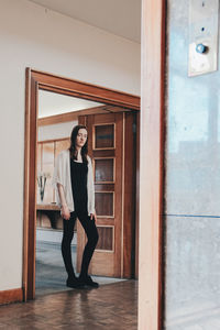 Portrait of woman standing against door