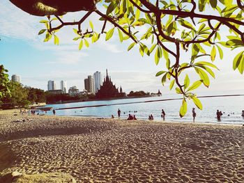 People on beach against sky in city