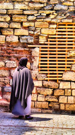 Rear view of woman standing against brick wall