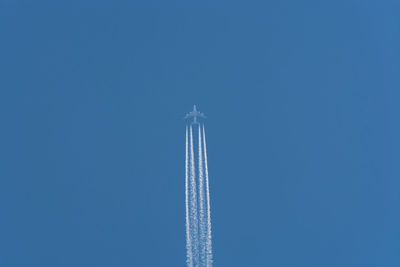 Low angle view of airplane flying against clear blue sky