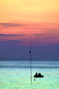 Silhouette people on sea against sky during sunset