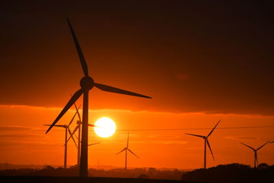 Silhouette windmill on field against sky during sunset