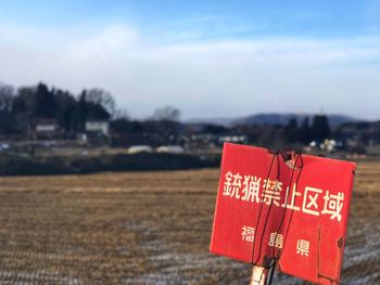 Close-up of red text on landscape against the sky